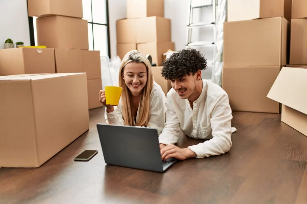 Young beautiul couple drinking coffee and using laptop at new home